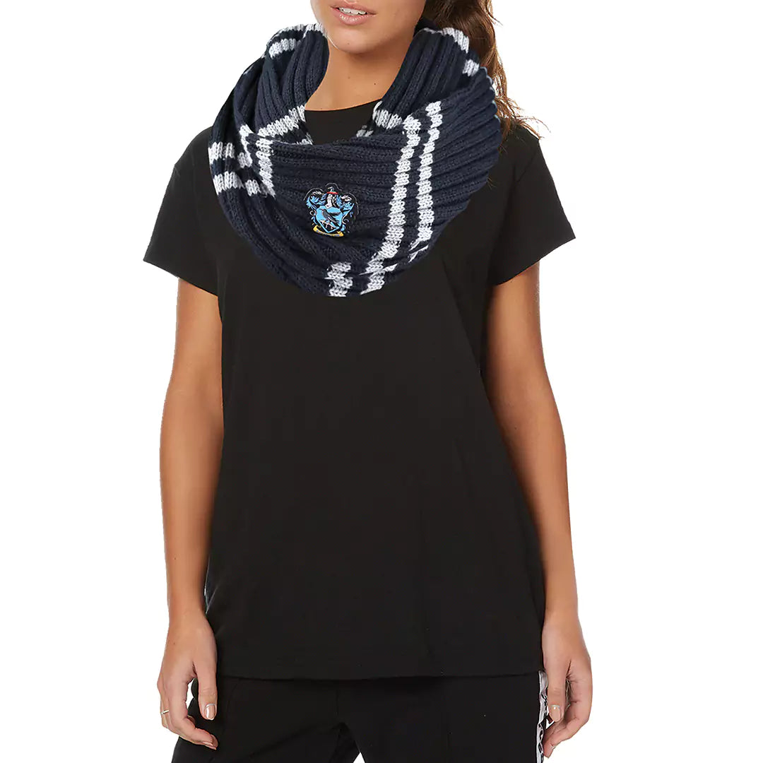Donkerblauwe, gebreide colsjaal met lichtgrijze strepen en een Ravenklauw-wapen, in lussen om de hals gedragen. Het model staat met de armen omlaag, draagt een zwart T-shirt en staat voor een witte achtergrond.