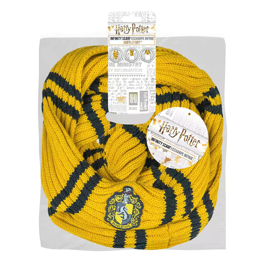 Gele gebreide Huffelpuf-infinitysjaal met zwarte strepen en een geborduurd wapen, in lussen gevouwen op een lichtgrijze kaart tegen een witte achtergrond. Aan de sjaal hangen Harry Potter-productlabels.