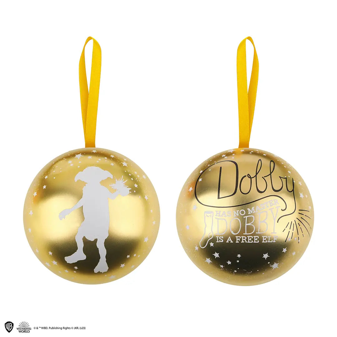 Twee aanzichten van een glanzende goudkleurige bol met geel ophanglint, tegen een witte achtergrond. Links een wit silhouet van Dobby met sterren; rechts de tekst ‘Dobby has no master, Dobby is a free elf’ in zwart en wit.