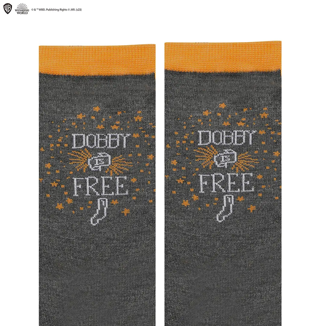 Twee donkergrijze, gebreide sokken met oranje boorden liggen naast elkaar op een witte achtergrond. Op beide staan oranje sterretjes, de witte tekst ‘DOBBY FREE’ en een wit sokje.