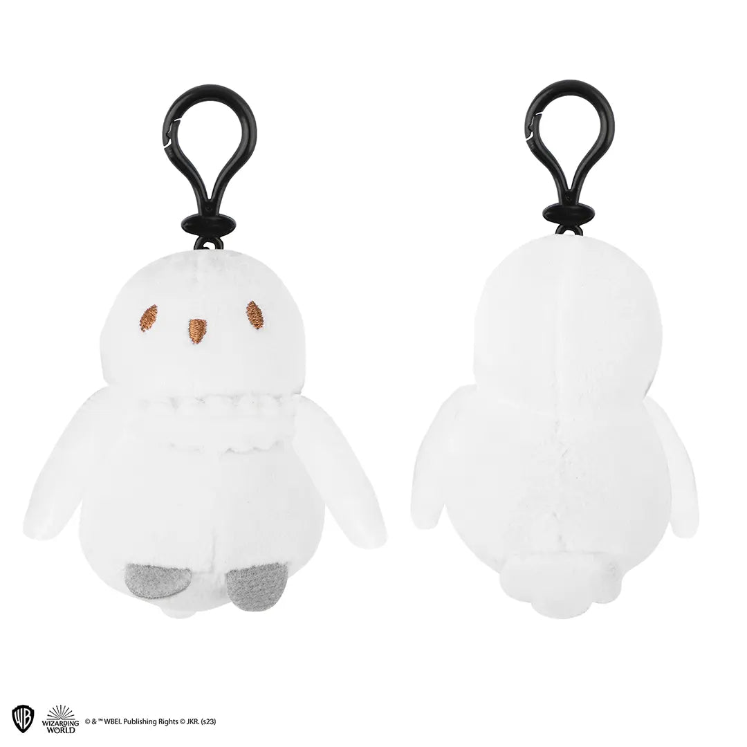Voor- en achteraanzicht van een witte pluche Hedwig-sleutelhanger met zwarte kunststof clip, bruin geborduurde ogen en snavel en grijze pootjes. De uil hangt rechtop met de vleugels omlaag tegen een witte achtergrond.