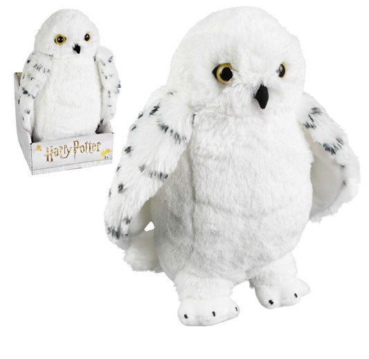 Witte pluchen Hedwig-uil met gele ogen, zwarte snavel en zwartgevlekte, afhangende vleugels, rechtop op een witte achtergrond. Linksboven staat dezelfde knuffel kleiner afgebeeld in een open Harry Potter-verpakking.