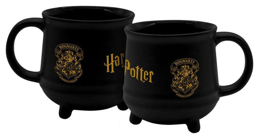 Twee aanzichten van een zwarte keramische ketelmok met rond oor en korte pootjes. De mok heeft een goudkleurig Zweinsteinwapen en Harry Potter-logo en staat tegen een witte achtergrond.
