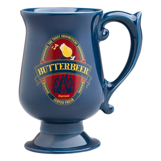 Glanzende donkerblauwe keramische beker op voet met een groot, gekruld oor rechts. Op de voorkant staat een rood-geel embleem met ‘Butterbeer’, een bierglas en een gebouw, tegen een witte achtergrond.