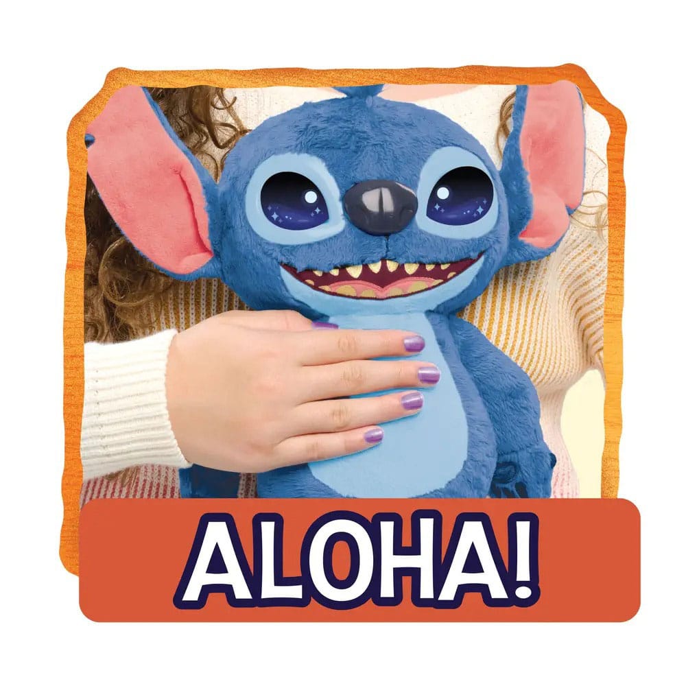 Blauwe pluchen Stitch met roze binnenoren, lichtblauwe buik, grote ogen en open mond met tanden, rechtop tegen iemand in een lichte trui. Een hand rust op zijn buik; de foto heeft een oranje rand en onderaan de tekst ‘ALOHA!’.