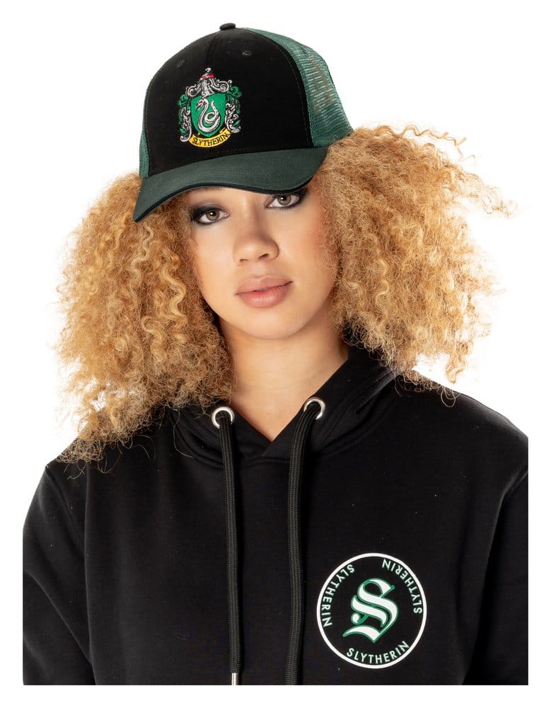 Zwarte truckerpet met groen mesh, gebogen groene klep en geborduurd Zwadderich-wapen op de voorkant. Gedragen door een model met blonde krullen en een zwarte hoodie, recht van voren tegen een witte achtergrond.