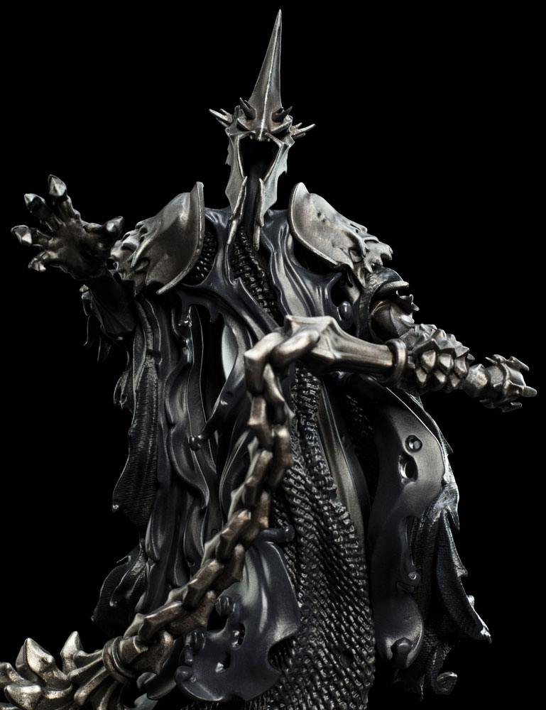 Kunststof beeldje van de Witch-King in een zwarte mantel en metaalgrijs harnas met hoge, puntige helm. Hij strekt één hand uit en houdt met de andere een ketting met stekelige strijdvlegel vast, tegen een zwarte achtergrond.